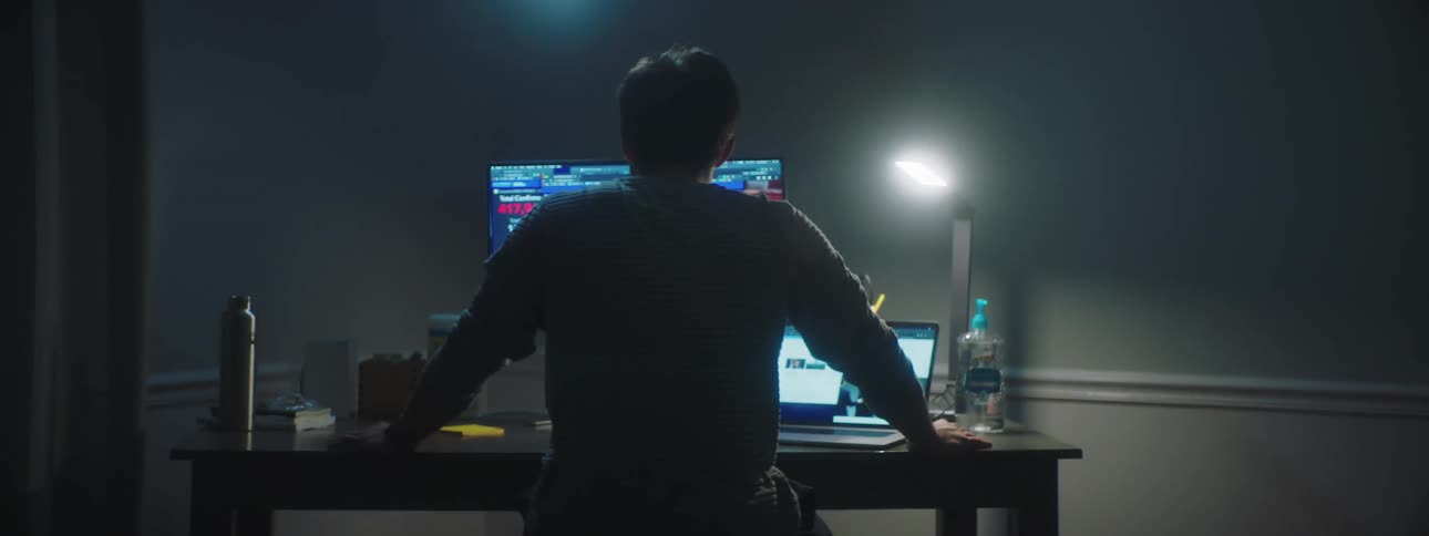 A man works at his computer desk inside a home