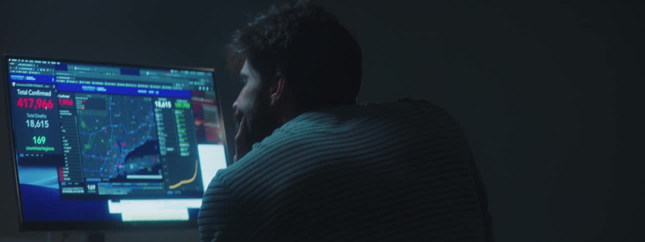 Man sitting at the desk uses the desktop in a dim lit room