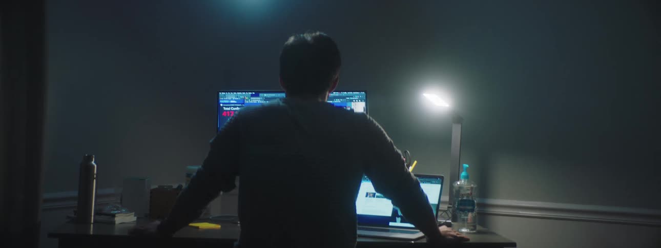 Man checks the coronavirus casualties across the world on the desktop computer in a dim lit room