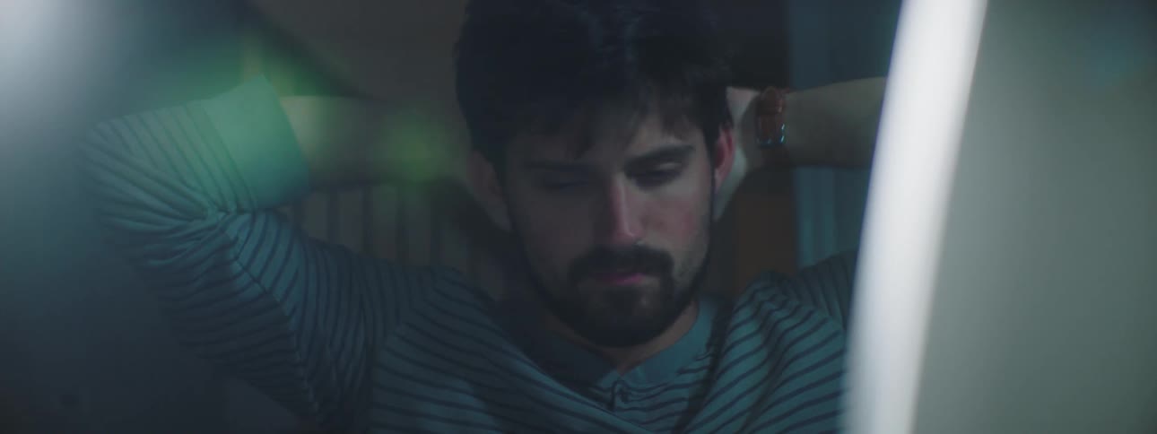 Man sitting at the desk checks the coronavirus casualties and shakes his head in disappointment in a dim lit room