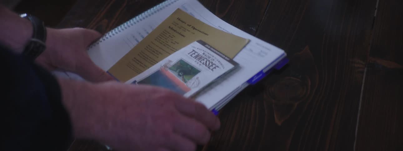 Brochures and booklet are being picked up from a wooden table