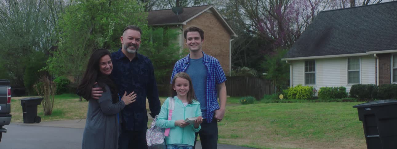 Family stands and poses for the camera in the neighborhood