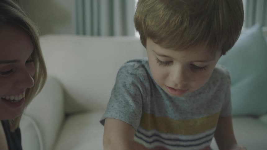 Kid picks up markers from box while mother watches smiling