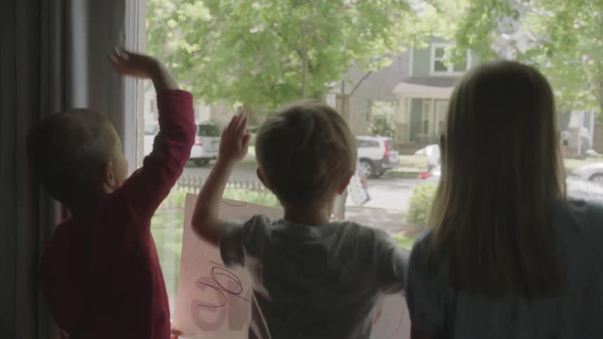 Children greet delivery man with signs in window