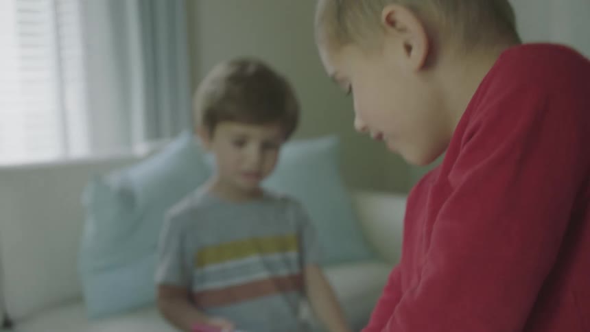A little boy smiles as he pulls a yellow marker out of a box held still by his mom