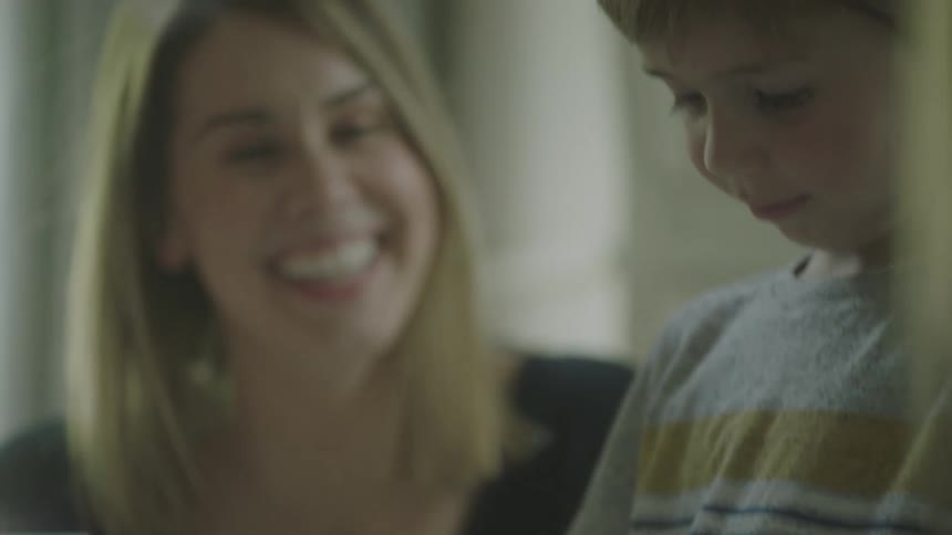 Woman smiles as a young boy concentrates