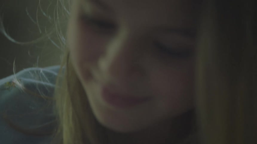 A young girl looks down and smiles