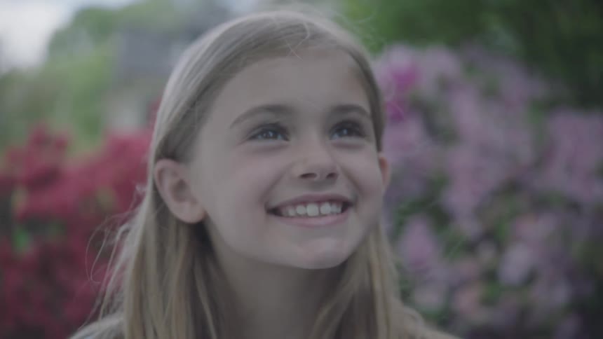 A portrait of a little girl positively beaming with pleasure in the garden