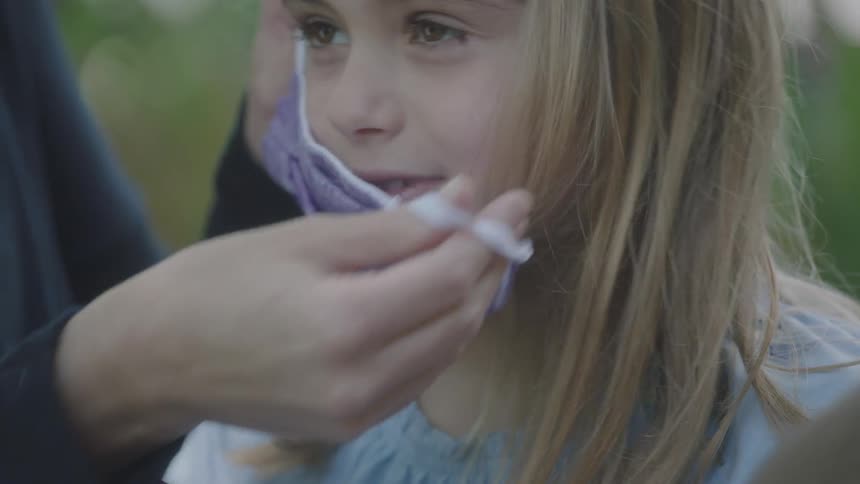 Girl uses inhaler then another person fastens face mask on her