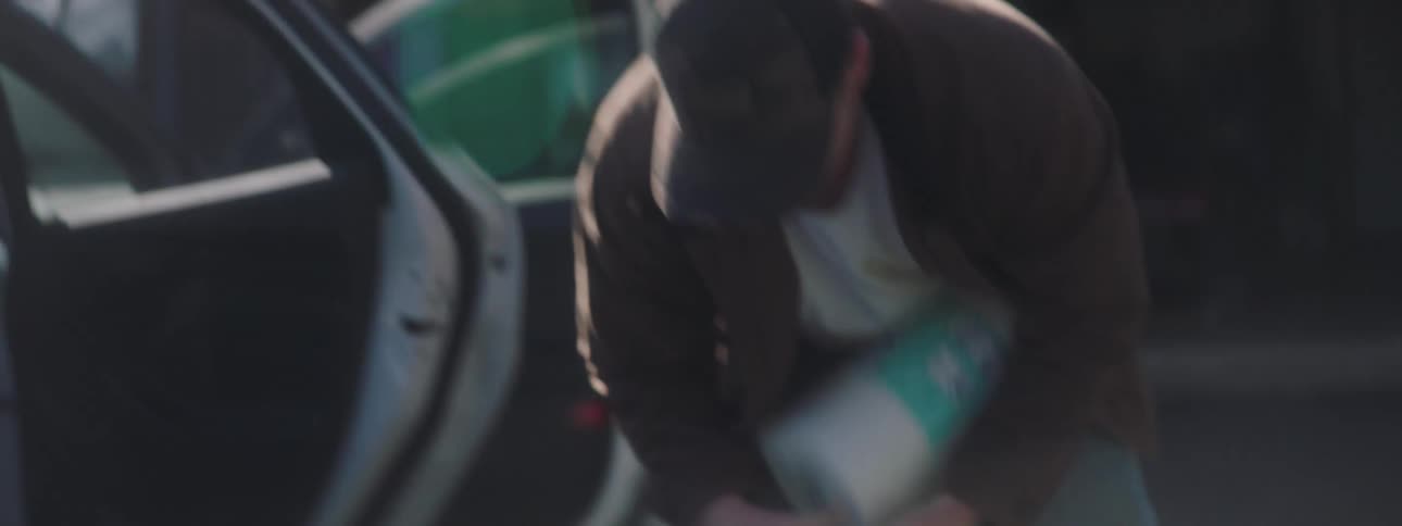 A man unloads stacks of paper towels into the ground from his car