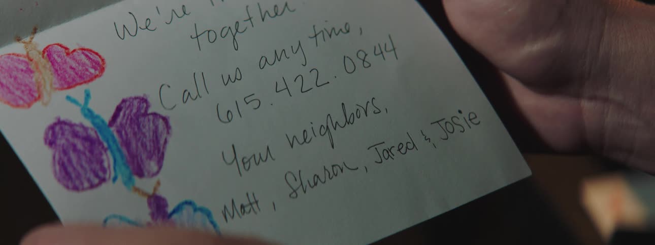 Person holds hand made card with caring message from neighbors