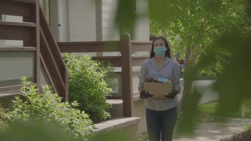 Woman walks and carries a food box as a precaution against corona virus