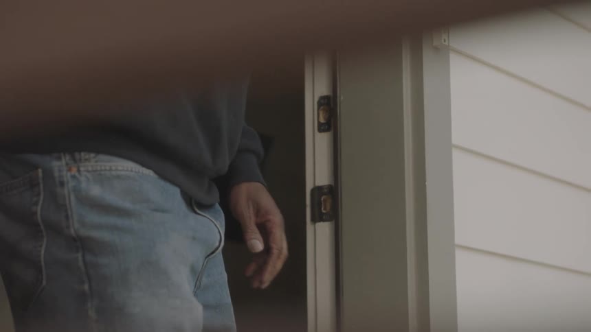 Elderly man picks up groceries box outside house