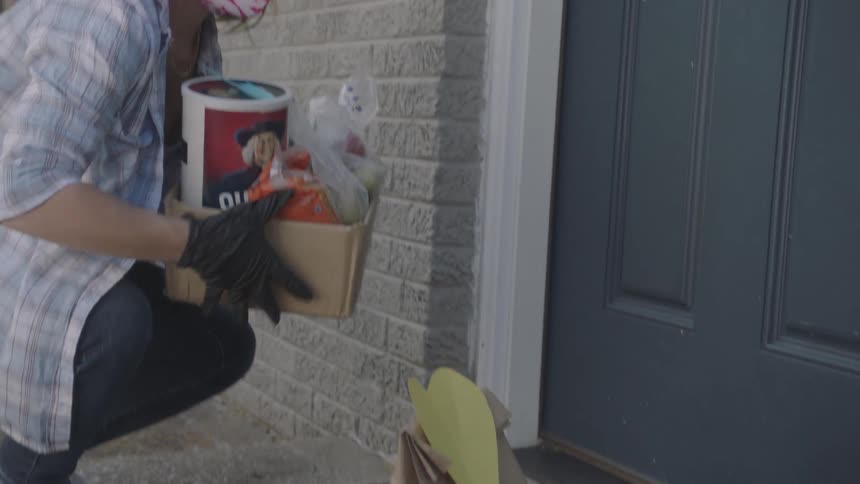 Young woman delivering supplies and placing on porch during the pandemic