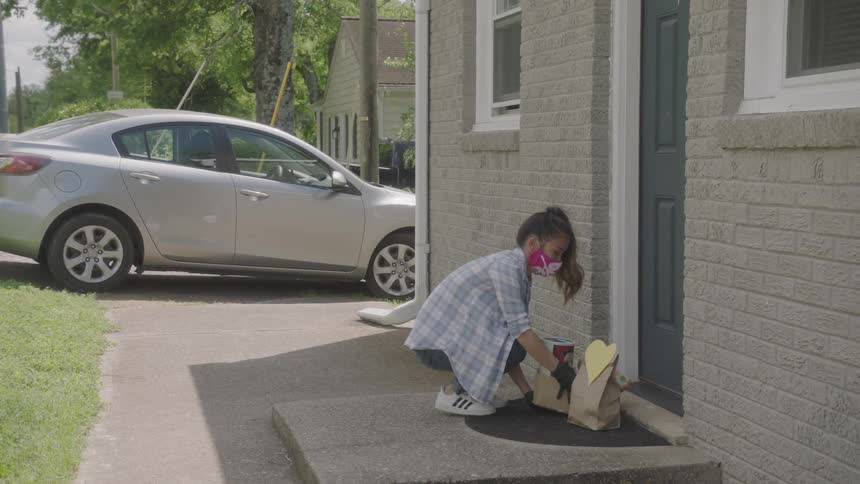 A young girl delivers items to a house