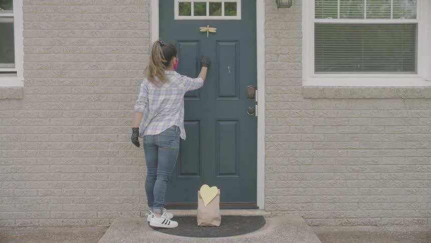 A young girl leaves a bag on a doorstep