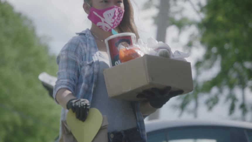 Woman wearing a mask and gloves delivers groceries to a front porch