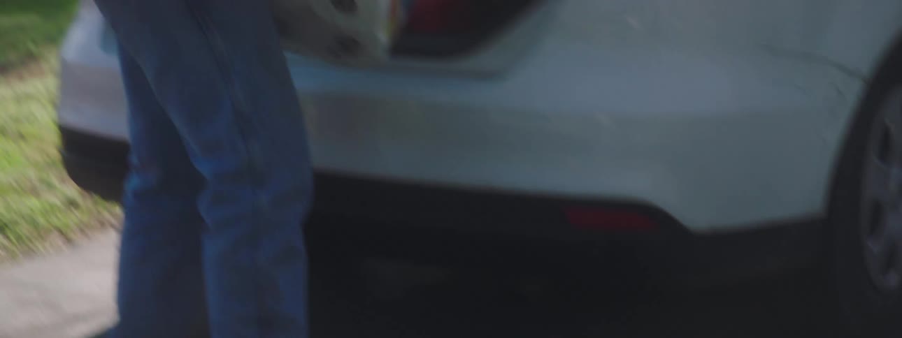 A man unloads toilet paper and gas cans from the trunk of his car