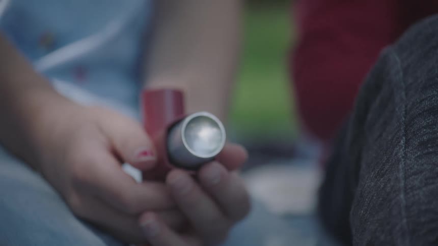 Close up of female holding an asthma inhaler while sitting next to friend