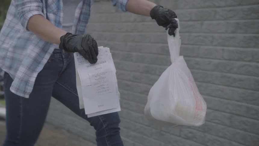Woman wearing gloves delivers groceries at doorstep