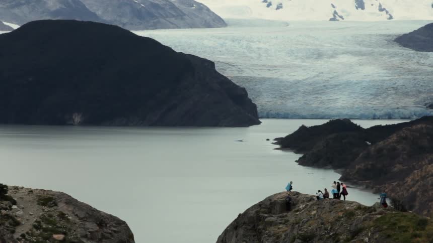 People gathered on top of cliff next to a body of water