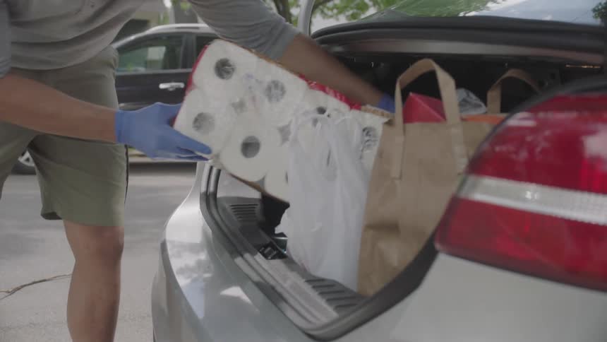 Man takes toilet paper from the trunk of the car