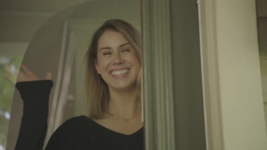 A woman is standing by a door and smiling