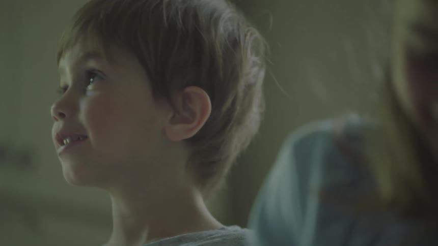 A boy smiles and laughs as his sister looks at him before turning her head to write