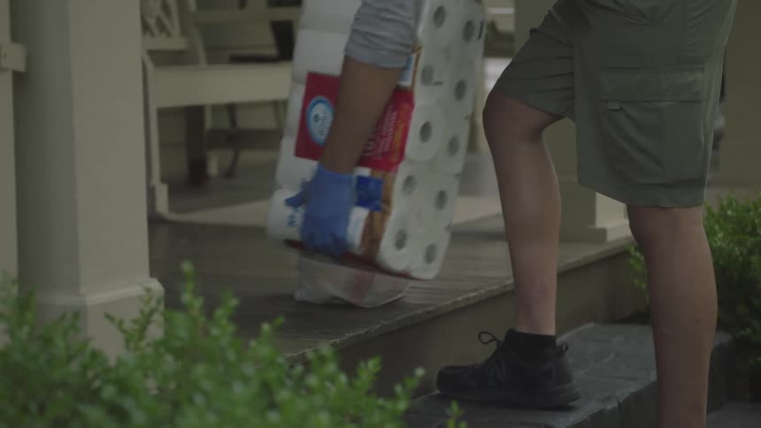 Man wearing gloves delivers groceries at doorstep
