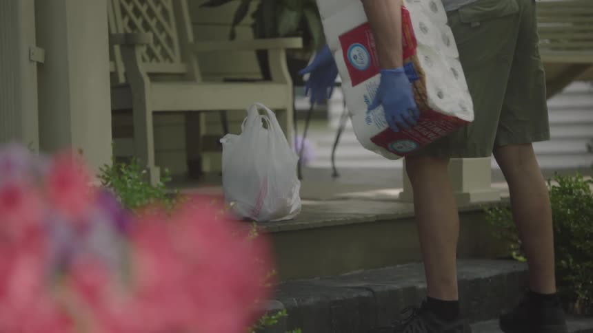 Man wearing mask and gloves delivers groceries at house doorstep