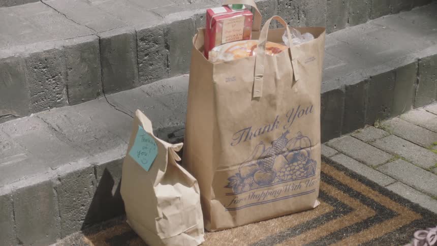 Woman wearing gloves delivers groceries at doorstep