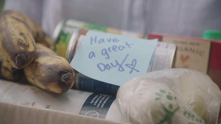 A cardboard box filled with food and a note