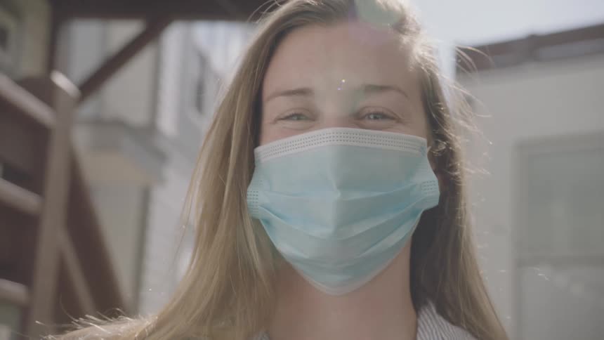 Blonde woman wearing a face mask smiles happily
