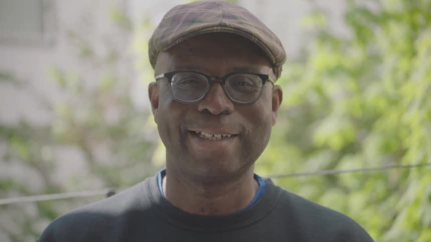 A man standing outside smiles on a sunny day