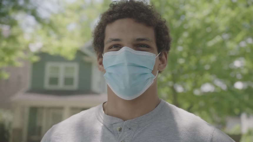 Young man wearing a face mask standing in middle of neighborhood