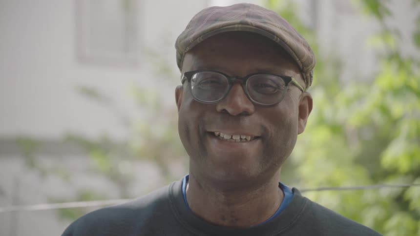 Man wearing hat and glasses looks up to the camera
