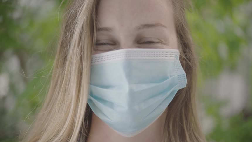 A teenager wearing a mask smiles outside