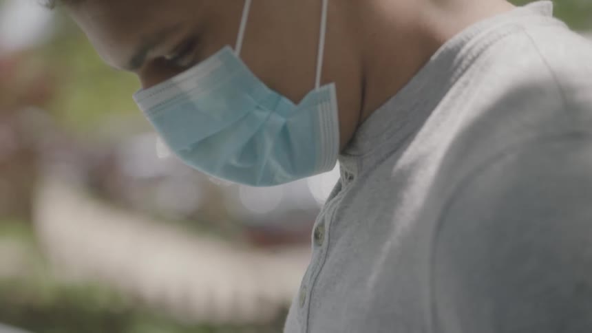 Man wearing a face mask looks down and raises his head in the neighborhood