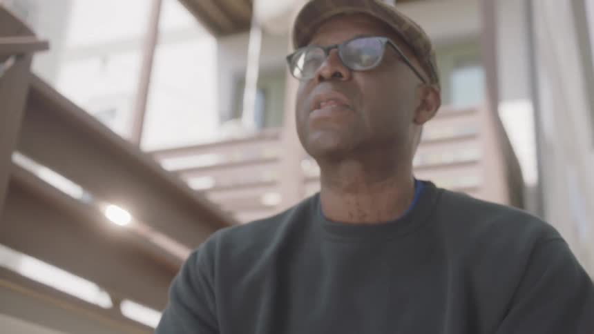 A man sits outside a house on the steps and look in to the distance