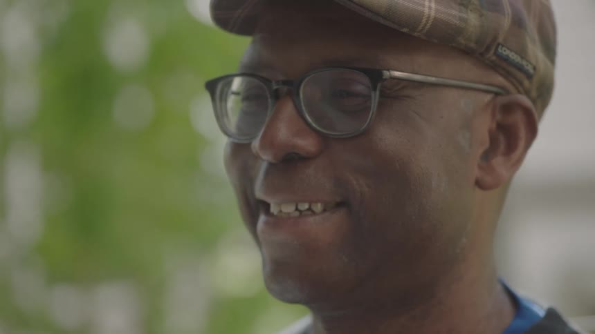 A black man lifts his head up and smiles