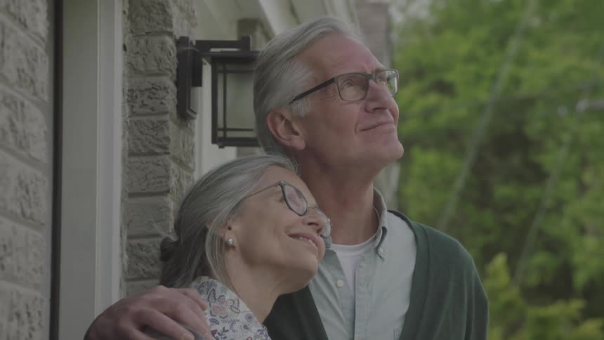 Older couple standing out on front porch enjoying the view