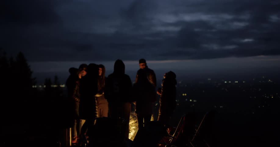Group of friends talking and laughing around a campfire