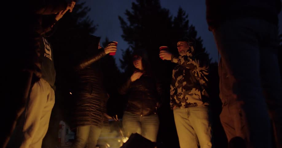 Friends hanging out by a bonfire outdoors in the wilderness