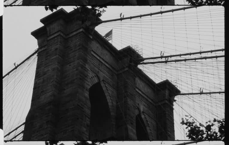 Vintage film of american flag waving atop brooklyn bridge in new york