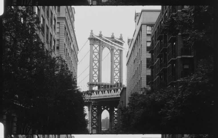 City buildings and a bridge sit under a cloudy sky
