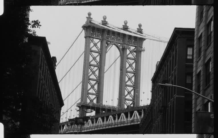 Cars traveling over a bridge seen from the city street with apartment buildings on both sides