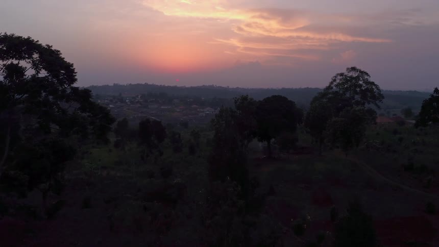 Sun turns cloudy sky on the horizon near the town red