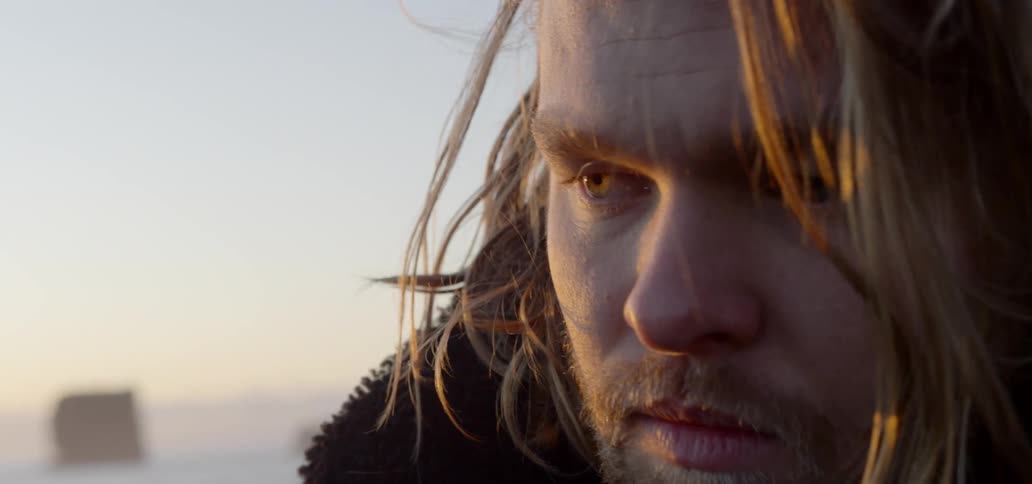 Close up of long haired mans face on the beach at sunset