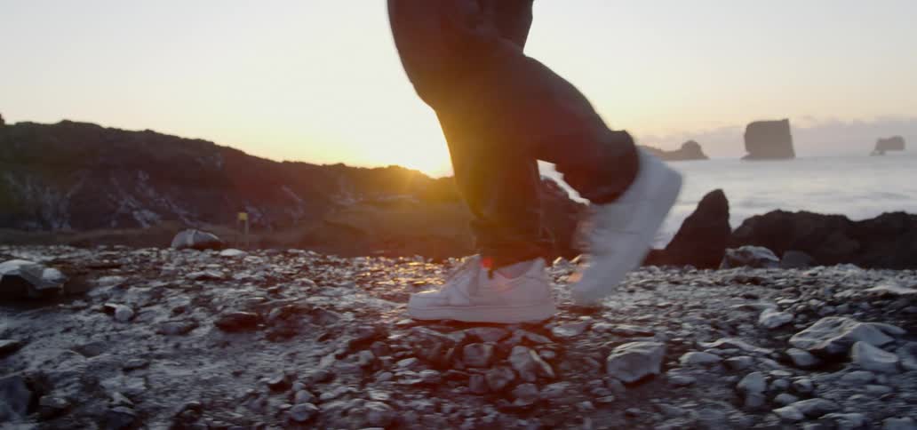 A man walks along a rocky shoreline