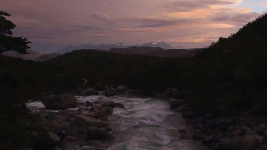 The sun sets over a river in the mountains